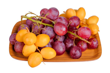 Fresh bunch of grapes and dates on plate isolated on white background