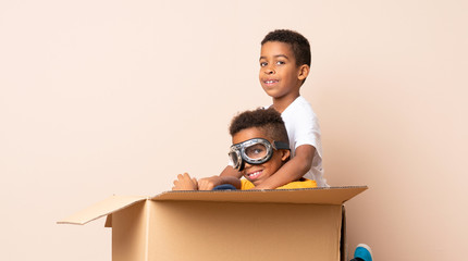 African American brothers playing. Boy inside a cardboard box with aviator glasses