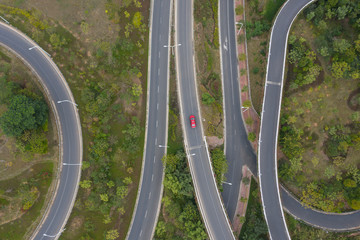 Top view of a red car walking through a densely curved bridge road