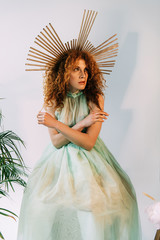 redhead girl with accessory on head in dress posing with crossed arms