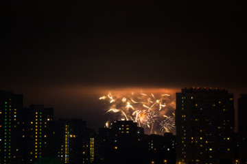 Colorful fireworks over the night city from the height of roofs