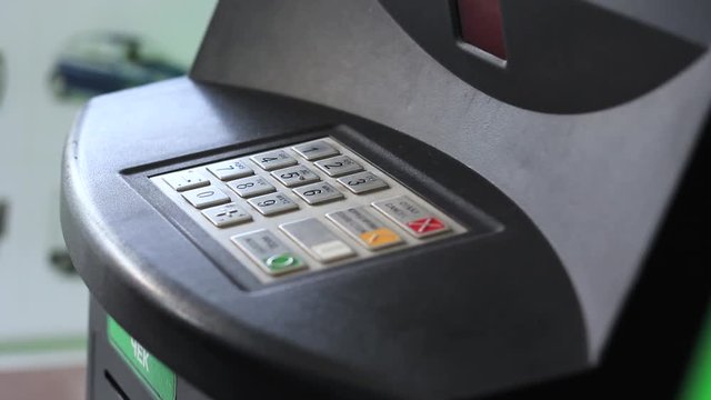 Female hand of an old woman dials a pin code at an ATM close-up