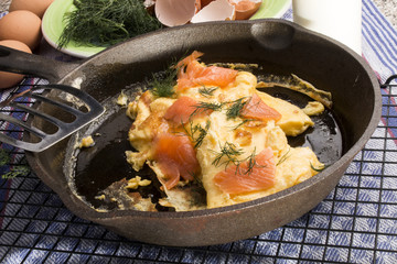 Scrambled eggs with salmon and dill in a pan