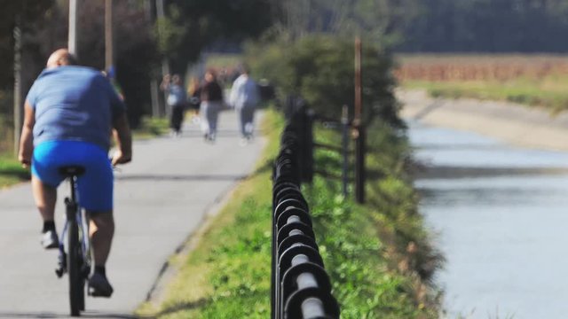 fat man cycling on a countryside road near a river