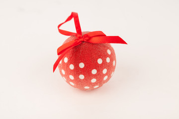 Red christmas ball with white dots and red ribbon on white background