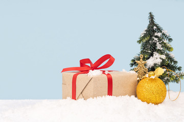 Cute santa claus doll with gold ornament, gift box, christmas tree and bell on snow. copy space on blue background.