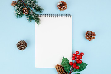 Blank white notepad among christmas decorations on blue background, top view, text space