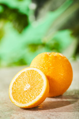 selective focus of cut and whole oranges with drops on marble surface