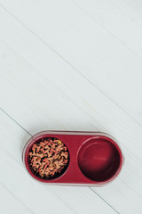 top view of bowl with dog food on white wooden surface