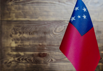 Fragment of the flag of the Independent state of Samoa in the foreground blurred wooden background...