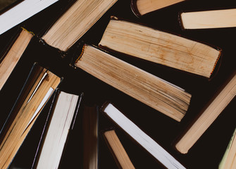 many old and used hardback books or text books seen from above , Old books . Group of old used open hardback books in dust on dark wooden background. Books textbooks for reading and education.