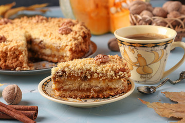 Homemade pumpkin pie with cinnamon and walnuts on a plate, with a piece of cake and cup of coffee in the foreground, horizontal orientation