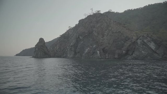Pznoramic view of an island cliff from boat in the sea, s-log ungraded