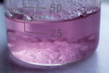A beaker with a saturated solution of manganese sulphate. The process of salt crystallization began on the bottom and on the inner surface of the beaker.