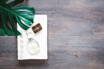 Organic soap bar with clear gel bath product with soft towel on rustic background. Spa time or pampering cosmetics flat lay with copy space