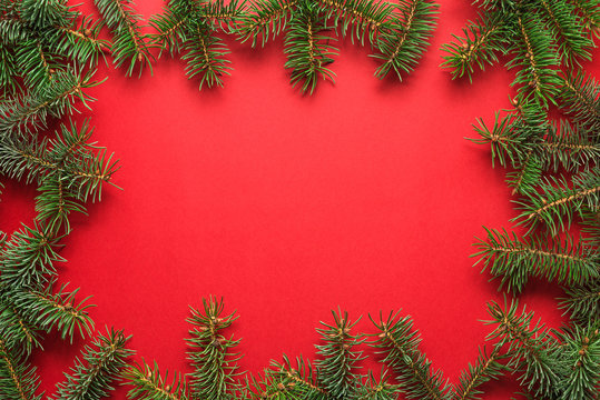 Christmas background. Frame made of fir tree branches on red background. Flat lay. top view