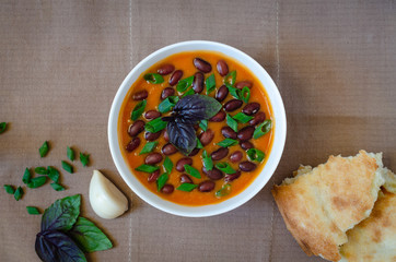 Bean puree soup with tomato, garlic, basil, onion and tandoor bread. Vegetarian food concept. Horizontal orientation. Flat lay.