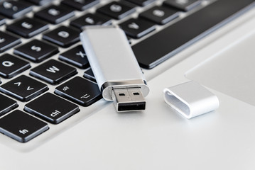 A silver USB flash drive on a laptop computer. 