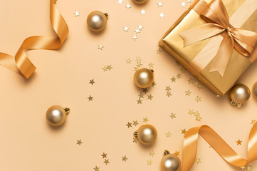 Merry Christmas and Happy Holidays greeting card. Beautiful golden gift balls ribbons confetti stars on gold background top view Flat lay. New Year presents Festive decorations 2020 celebration