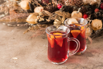Two glasses of christmas mulled wine with oranges and spices on a textural background. Selective focus. Copy space.