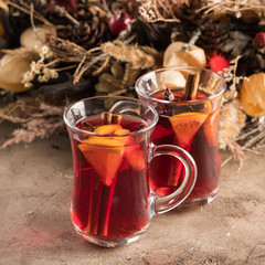 Two glasses of christmas mulled wine with oranges and spices on a textural background. Selective focus. Copy space.