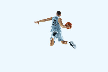 Fototapeta na wymiar High flight. Young caucasian basketball player of team in action, motion in jump isolated on white background. Concept of sport, movement, energy and dynamic, healthy lifestyle. Training, practicing.
