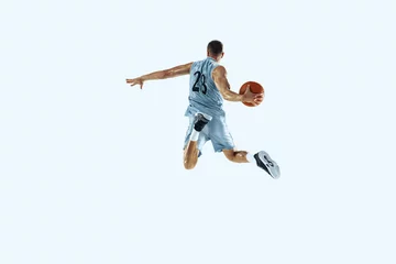 Tuinposter High flight. Young caucasian basketball player of team in action, motion in jump isolated on white background. Concept of sport, movement, energy and dynamic, healthy lifestyle. Training, practicing. © master1305