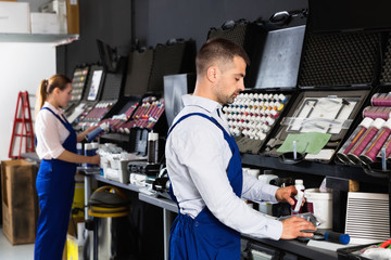 Professional car painter preparing paints for paintwork in modern auto repair shop