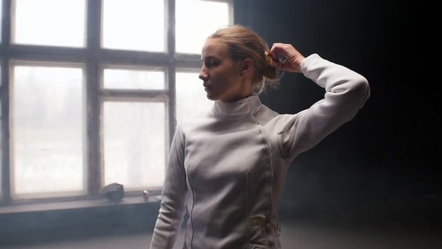 A young woman fencer she lets her hair down and shakes her head