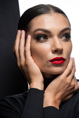Fototapeta na wymiar beautiful woman with red lips posing with hands near face isolated on white and black