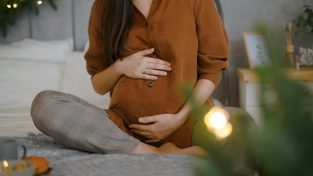 Pergnant womani on bed in christmas decorated room at Christmas morning