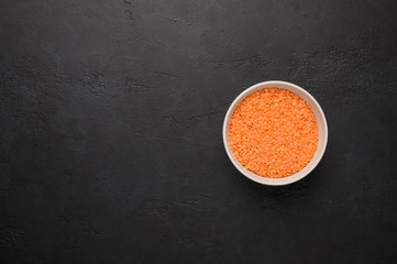 Bowl of lentils on a textured wooden black background. Vegetable protein healthy food
