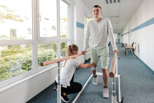 Therapeutin hilft jungem Mann, der nach einem Unfall in der Reha wieder laufen lernt