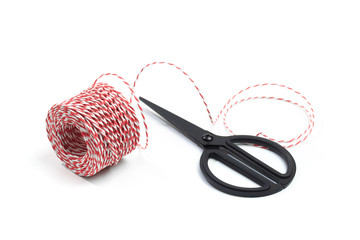 Red and white bakers twine rope spool and scissors isolated on white background. Packaging equipment or handicraft tool concept. - Image