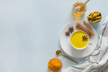 Cup of ayurvedic golden turmeric milk with honey and curcuma powder. Space for text or recipe. Healthy drink for immunity. Top view. Natural food. Trendy Asian beverage.