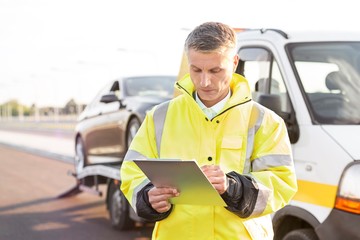 Tow truck driver writing report on clipboard