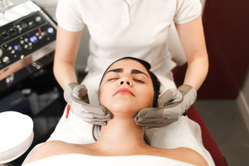 Obraz na płótnie Canvas Microcurrent therapy. Cosmelotologist makes stimulating facial massage with electric gloves. Lymphatic drainage massage
