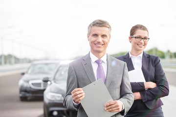 Business people standing on road against cars