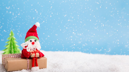 Santa sitting on Christmas gift near tree over background