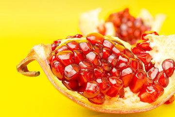Fresh organic pomegranate fruit close up macro isolated in yellow background.