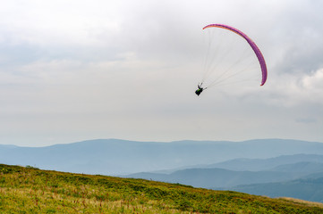Man on a paraglider, parachute wing, flies against the backdrop of a beautiful landscape at the peak of the Carpathian mountains..