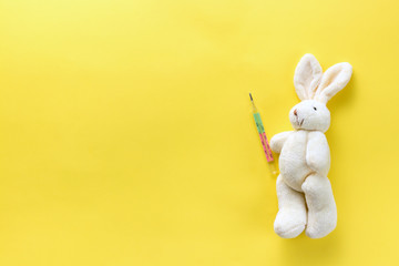 Children's toy with a medical thermometer. Soft toy hare and medical thermometer on a yellow...