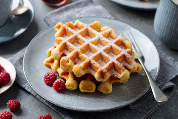 Belgian waffles with maple syrup and fresh raspberry. Grey background. Close up. - 302216740