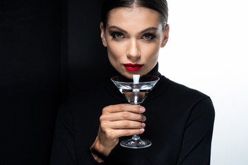 beautiful woman with red lips holding martini isolated on white and black