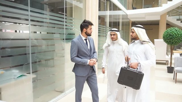 Two busy sheikhs and Caucasian businessman talking to each other. Speak about new deal, finance
