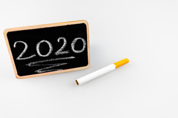 Noworocze postanowienie z rzuceniem palenia, papieros i tabliczka z rokiem © andsko