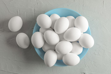 Chicken eggs in plate on gray background, space for text