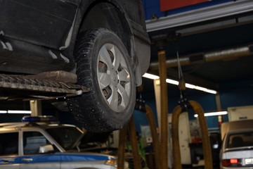 Fototapeta premium car on a lift in the garage for maintenance, wheel closeup