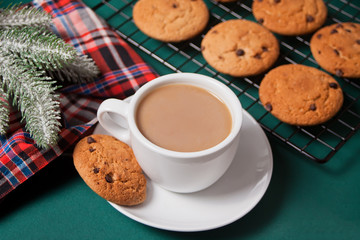 Cup of tea, homemade cookie, Christmas gift boxes and Christmas decor on the green background.