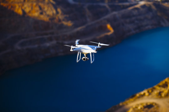 Uav drone copter flying with digital camera above opencast mining quarry.